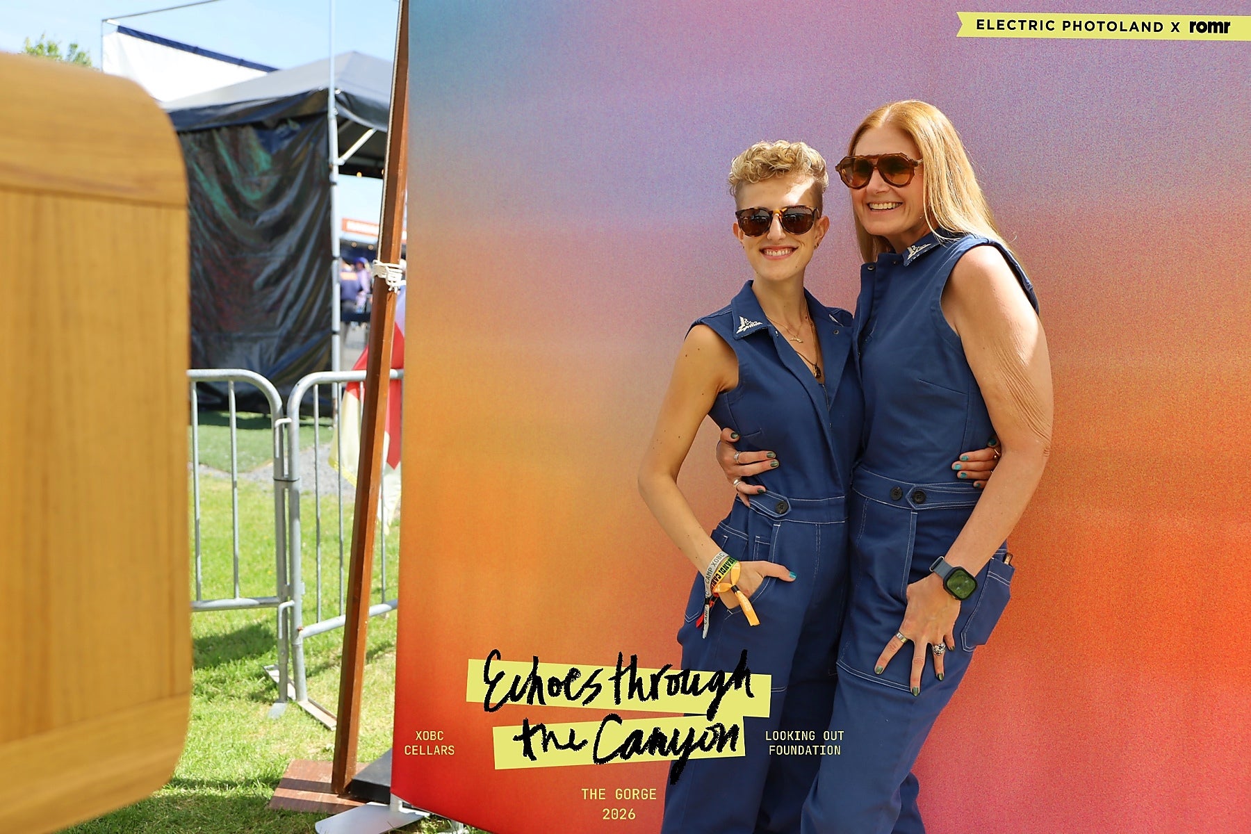 Two guests posing in front of the XOBC Cellars branded photo backdrop at The Gorge Amphitheatre